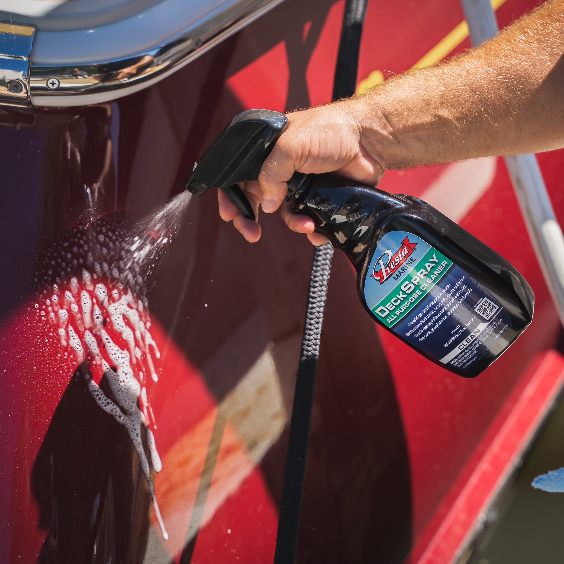 A person is spraying DeckSpray All-Purpose Cleaner on a surface.