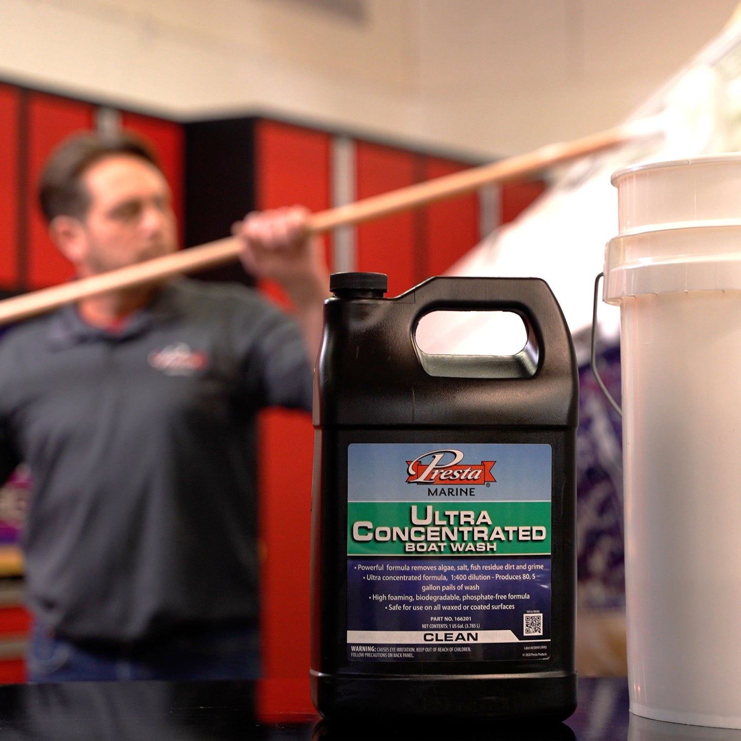 a person holding a Paint Stick in front of a Ultra Concentrated Boat Wash container