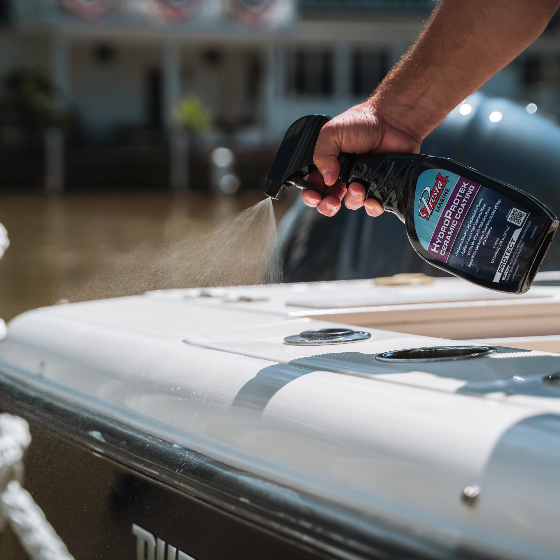 A hand applying HydroProtek Ceramic Coating to the surface of a boat